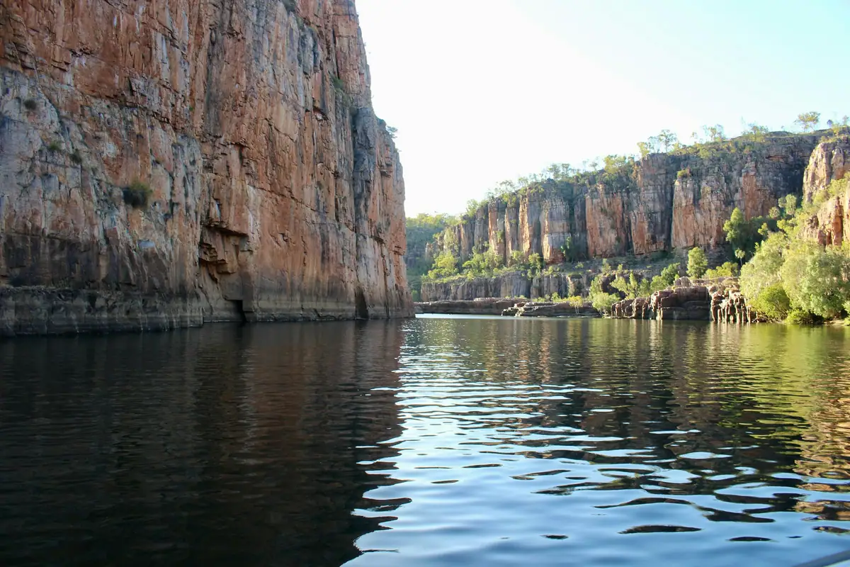 The Katherine River runs between tall orange sandstone cliffs in Nitmiluk Gorge, its water rippling in soft light