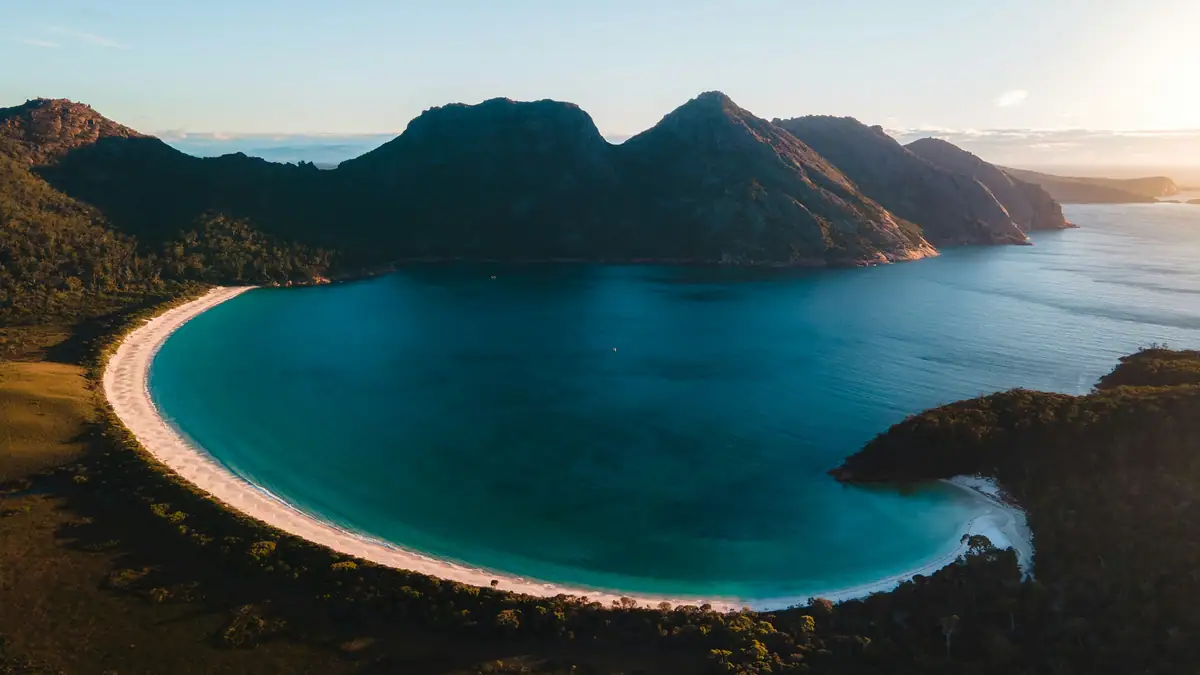 The white curve of Wineglass Bay and its turquoise water below the granite peaks of the Hazards, Freycinet National Park